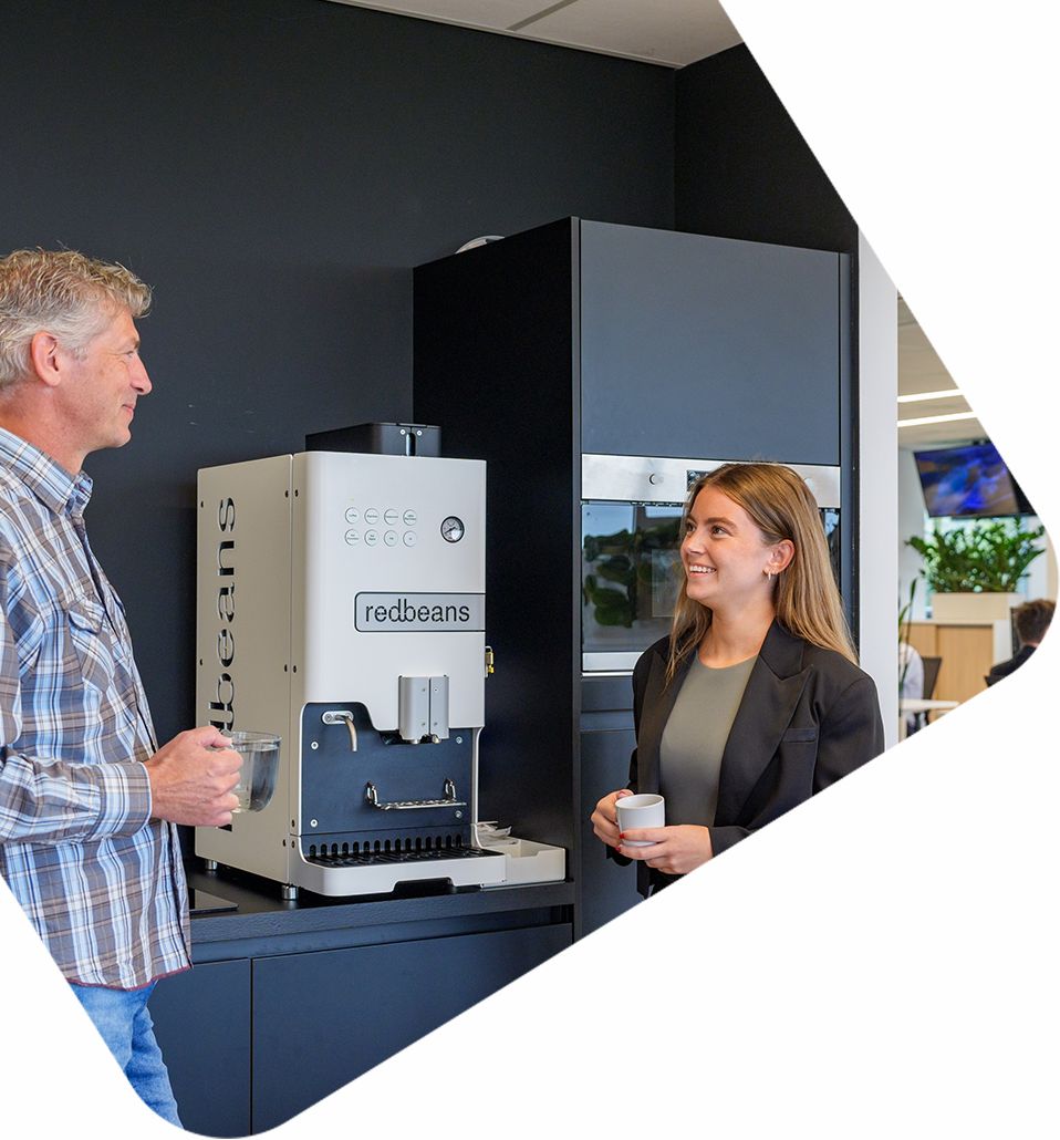 Collega’s overleggen informeel bij koffiemachine over systeemintegraties