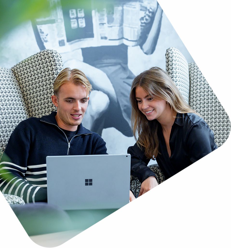 Twee medewerkers van reclamebureau overleggen bij laptop in moderne kantoorruimte