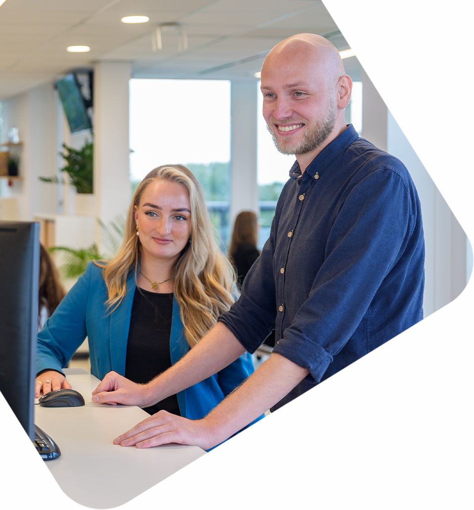 Twee medewerkers van bluedesk die samenwerken aan een computer in een moderne kantooromgeving een advies schrijven over het Digital Product Passport voor een klant.