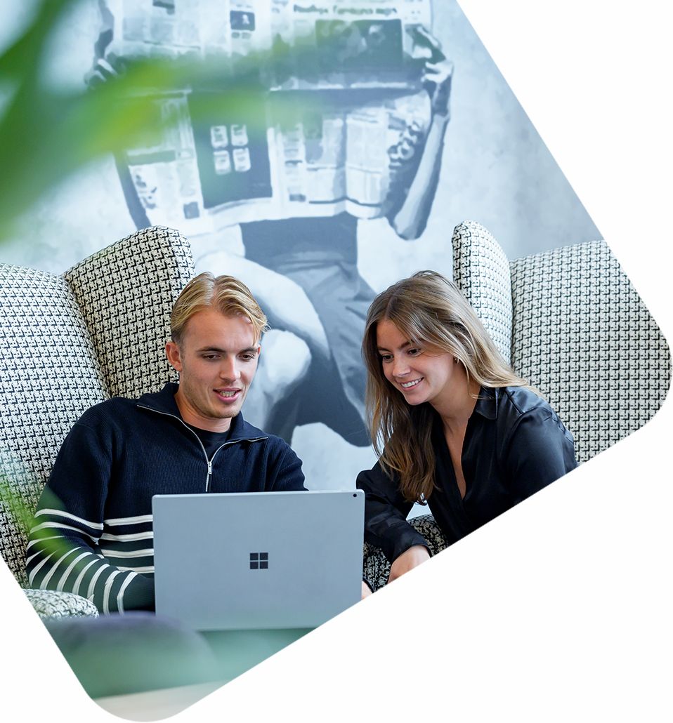 Jonge professional en collega samenwerkend op Microsoft‑laptop in lounge